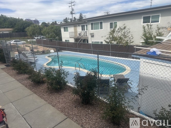 A pool surrounded by a fence and bushes.