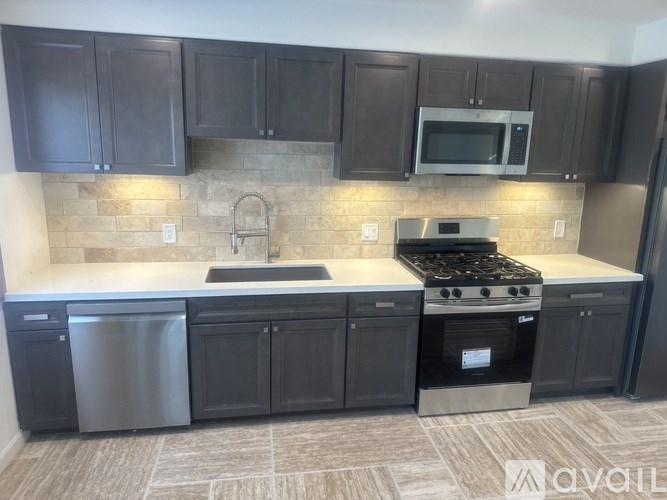 A kitchen with dark brown cabinets and a stainless steel dishwasher.