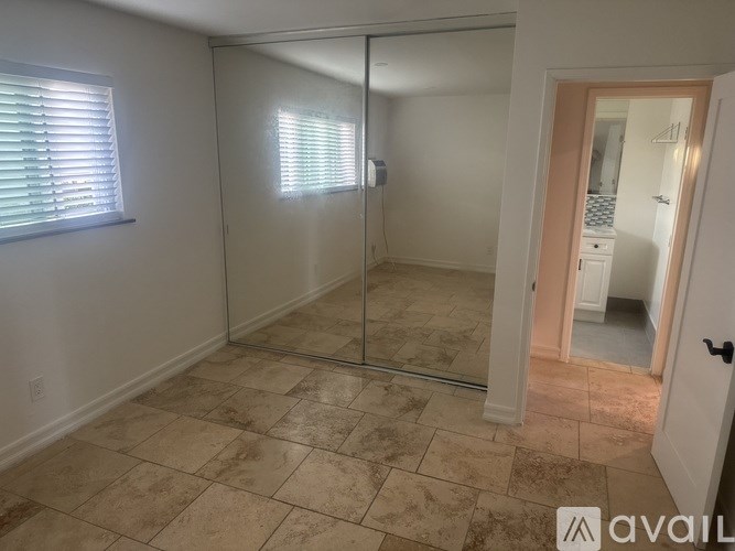 A room with a tiled floor and a sliding glass door leading to another room.