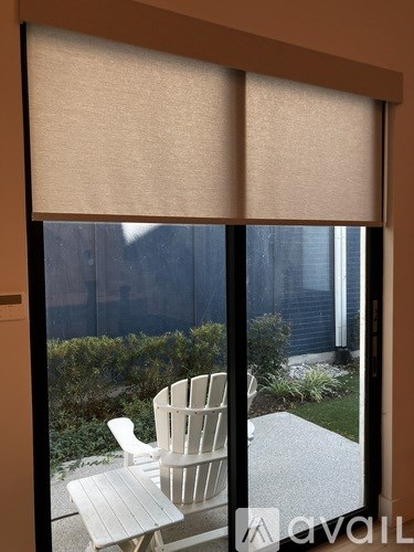 A white chair is on a patio outside a window.