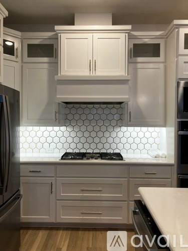 A kitchen with white cabinets and a hexagonal tile backsplash.
