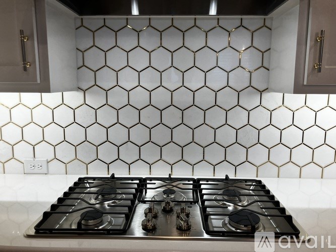 A kitchen with a black and white tiled backsplash and a stove top oven.