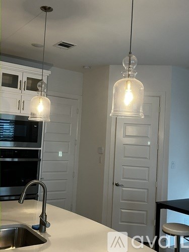 A kitchen with a sink and two hanging lights.