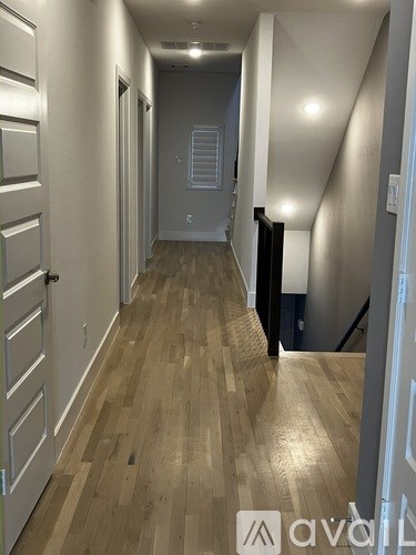 A hallway with wooden floors and white walls.