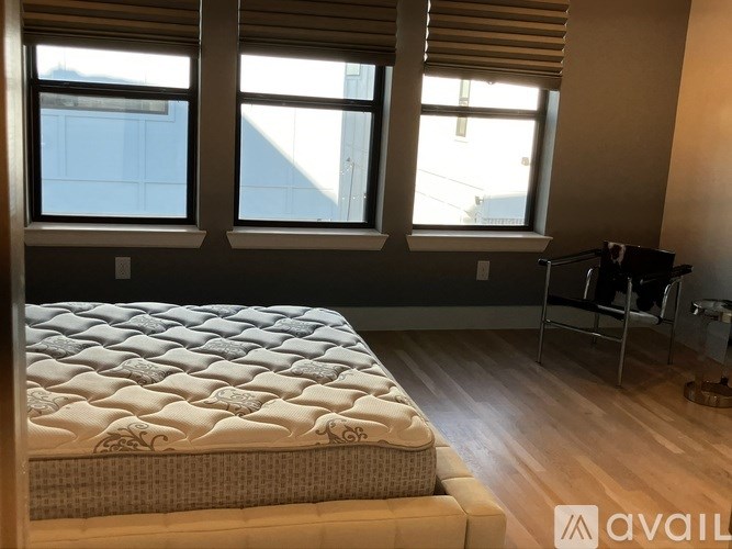 A bedroom with a large bed and a chair.