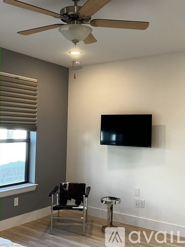 A room with a television on the wall and a chair in front of it.