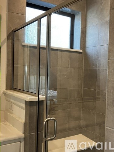 A glass shower door with a handle and a window.