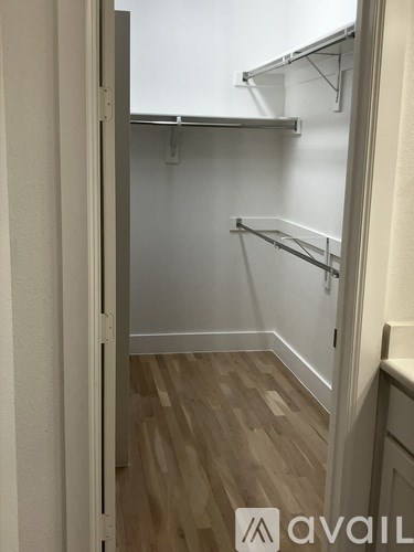 A white closet with shelves and a wooden floor.
