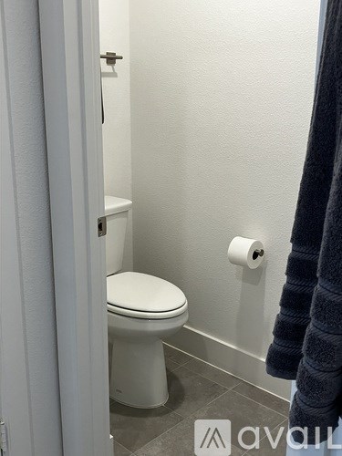 A white toilet in a bathroom with a towel hanging on the wall.