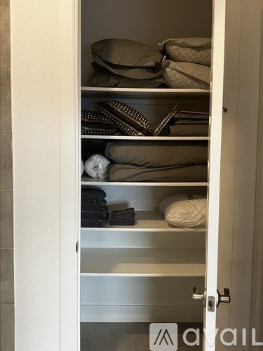 A white closet with shelves and clothes.