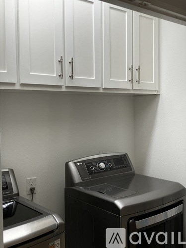 A black dishwasher is in front of a white wall and a black washing machine.