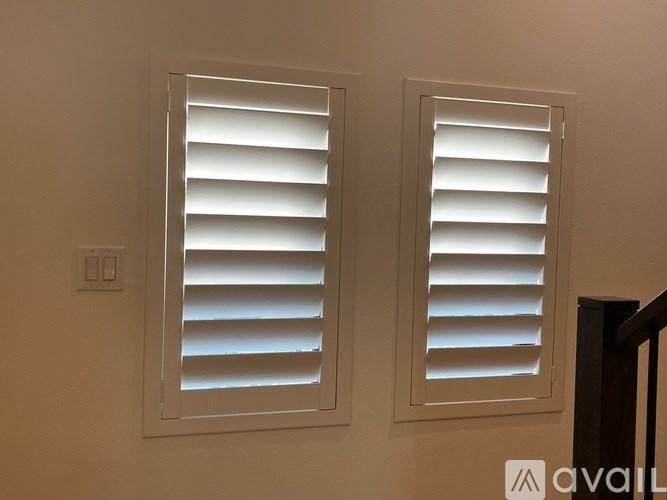 Two white window blinds on a wall.
