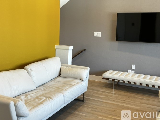 A white sofa sits in a room with a grey wall and a wooden floor.