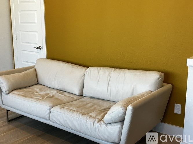 A white couch is placed against a yellow wall.