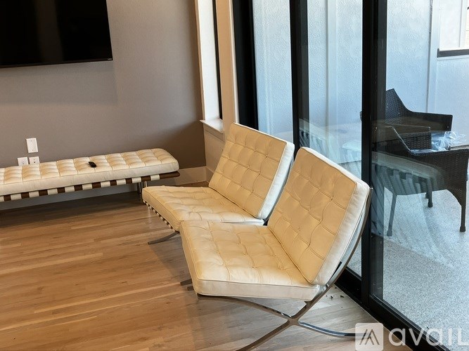 A white chair with a quilted back sits in a room with a glass wall.
