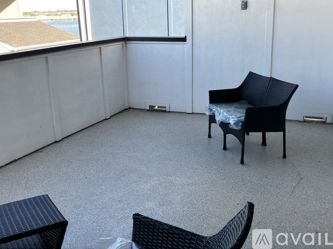 A black chair with a blue cushion is in a room with a large window.