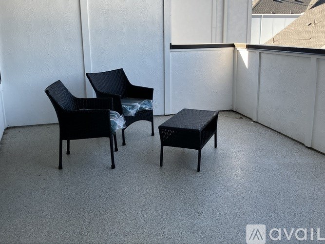 Two black chairs and a small table are in a room with white walls.