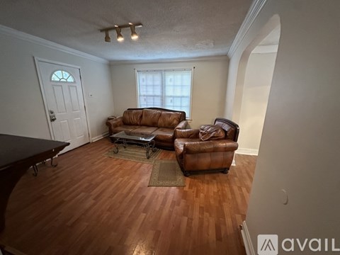 A living room with a brown leather couch and a wooden floor.
