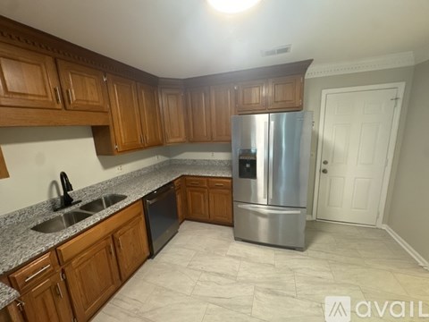 A kitchen with wooden cabinets and a stainless steel refrigerator.