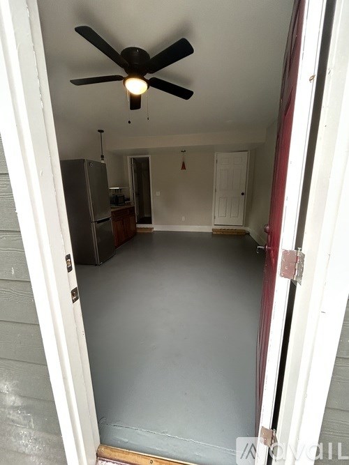 A room with a ceiling fan and a refrigerator.