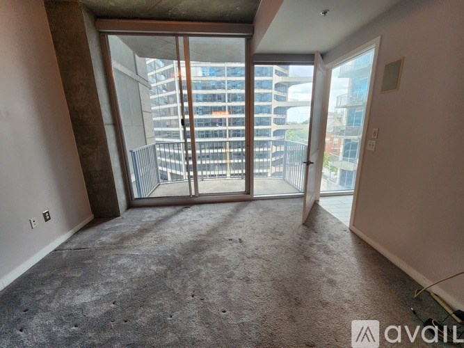 A room with a carpeted floor and a large window with a view of a cityscape.