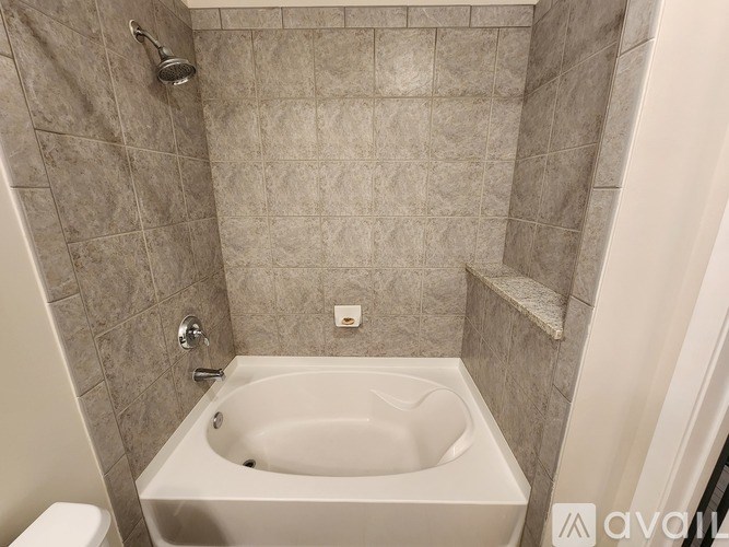 A white bathtub in a tiled bathroom.