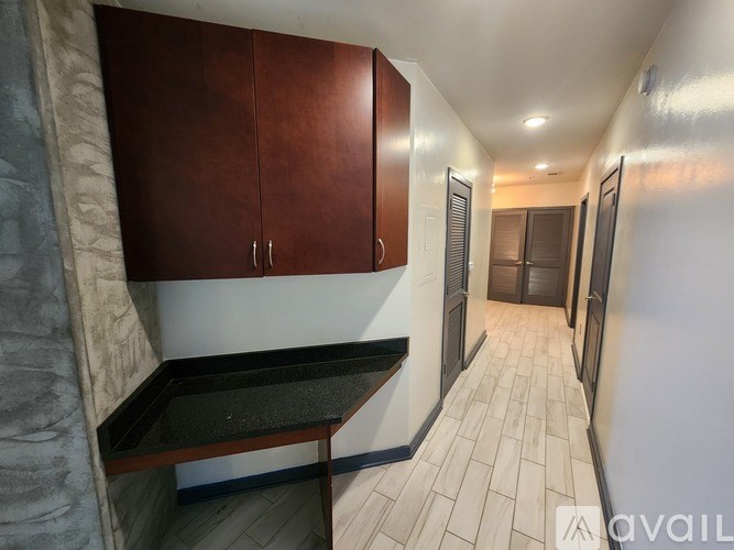 A long hallway with wood cabinets and a black counter top.