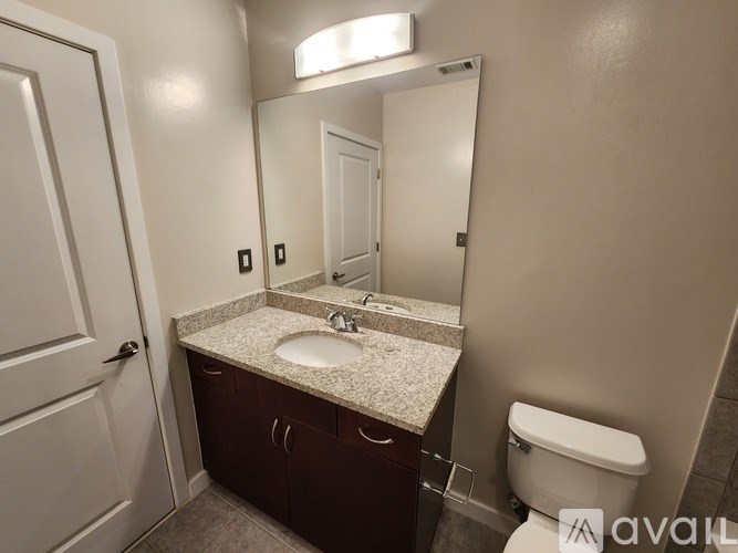 A bathroom with a sink, toilet, and mirror.