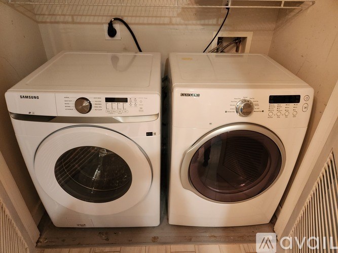 Two white front loading washing machines in a small space.