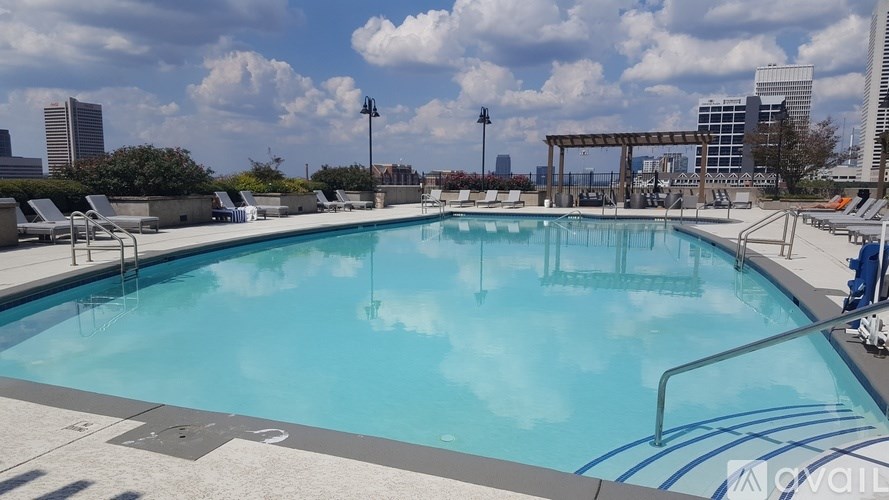 A large outdoor swimming pool with a blue tiled edge and a white diving board.