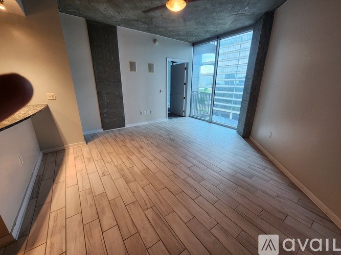 A room with wooden flooring and a balcony with glass doors.
