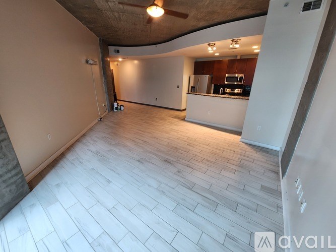 A spacious room with a kitchen area in the background.