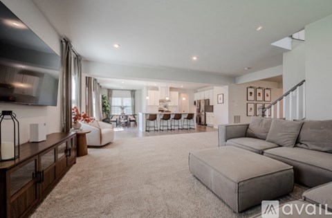 A modern living room with a grey sofa and a kitchen area in the background.
