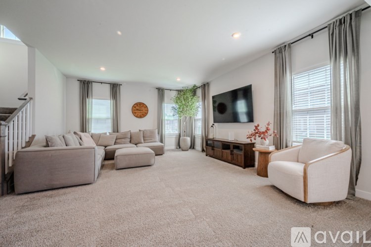 A spacious living room with a large grey sofa, a white armchair, and a wooden coffee table.