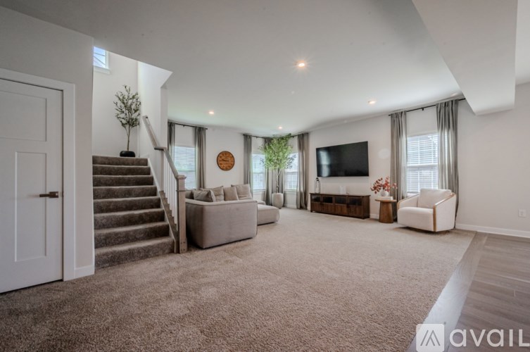 A spacious living room with a staircase and a flat-screen TV.