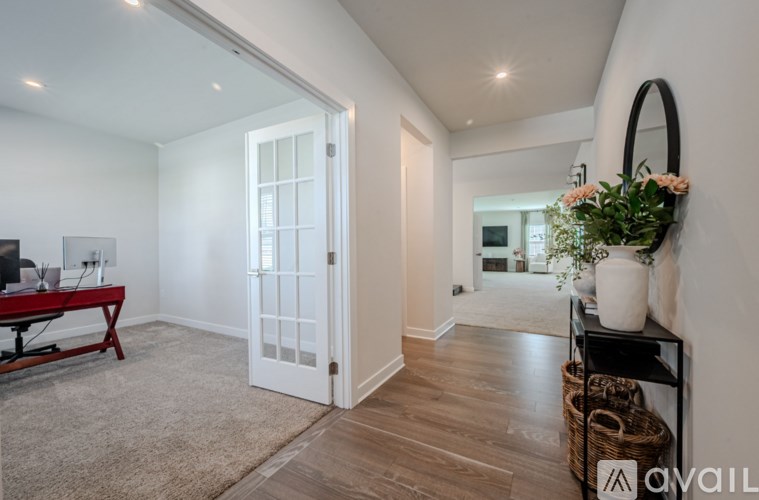 A room with a white door, a red table, and a plant on a shelf.