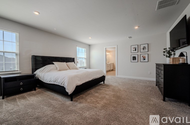 A bedroom with a large bed, carpeted floor, and a window with blinds.