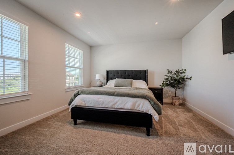 A bedroom with a large bed and a window with blinds.