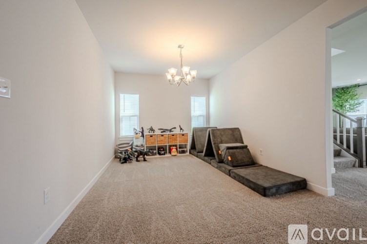 A spacious room with a grey carpet, a grey sofa, a grey chair, a grey ottoman, a grey couch, a grey table, a grey rug, a grey wall, a grey floor, a grey ceiling