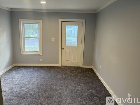 A room with a door, window, and carpeted floor.