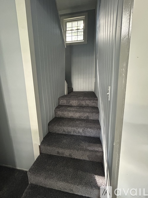 A staircase with a carpeted runner and a small window at the top.