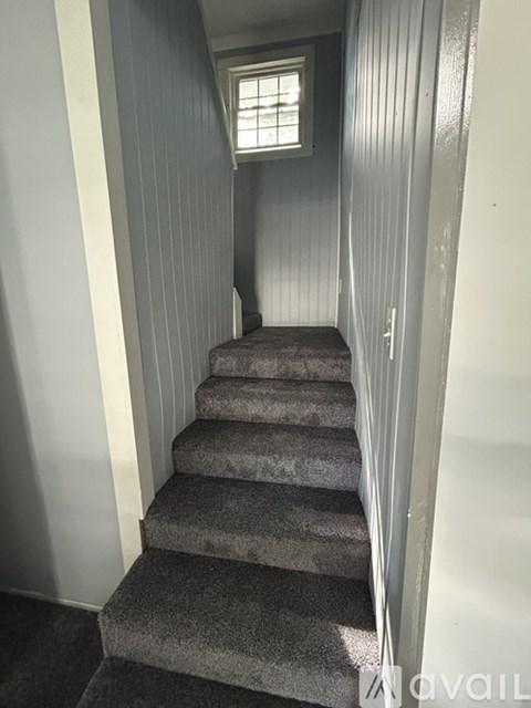 A staircase with a carpeted runner and a small window at the top.