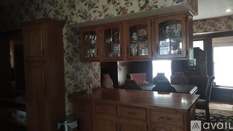 A kitchen with wooden cabinets and floral wallpaper.