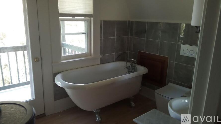 A white bathtub is in a bathroom with a toilet and sink.