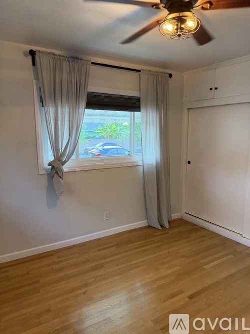 A room with a ceiling fan and a window with curtains.