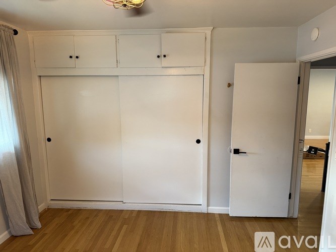 A room with a white door and a white cabinet with a light on the ceiling.