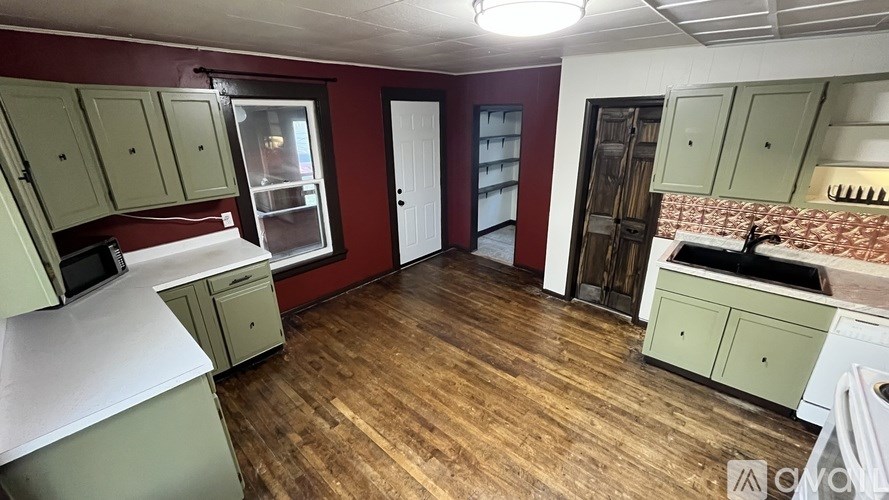 A kitchen with wooden floors and green cabinets.