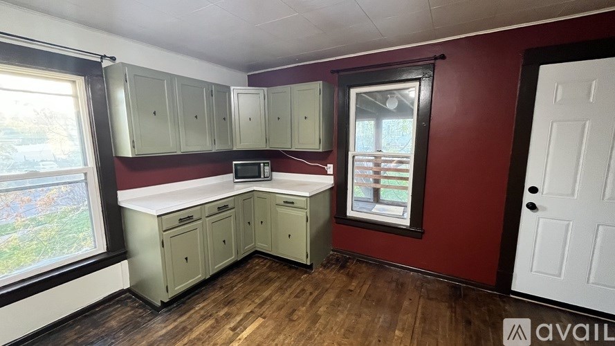 A kitchen with red walls and wooden floors.