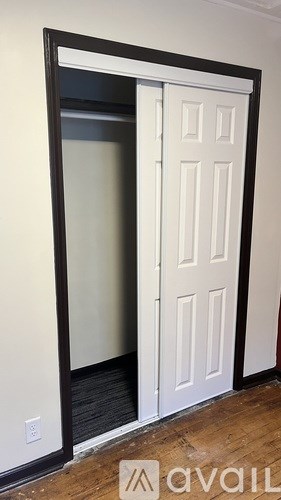 A white door with a black frame is in a room with a wooden floor.