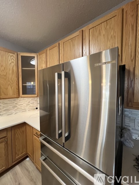 A stainless steel refrigerator in a kitchen with wooden cabinets.